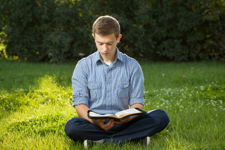 young-man-reading-bible-in-park-featured-w740x493